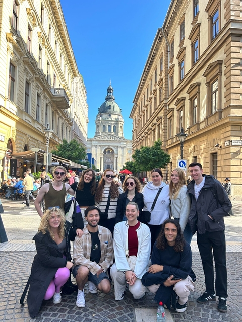 Group photo in a city with a grand building in the background.