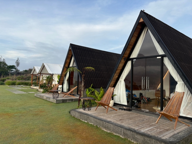 Row of triangular houses on a grassy area.