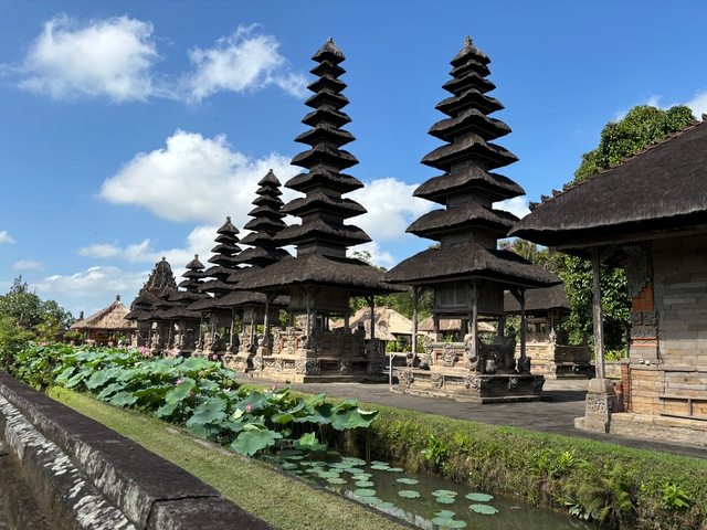 Traditional Balinese temple with multiple pagodas and lotus pond.