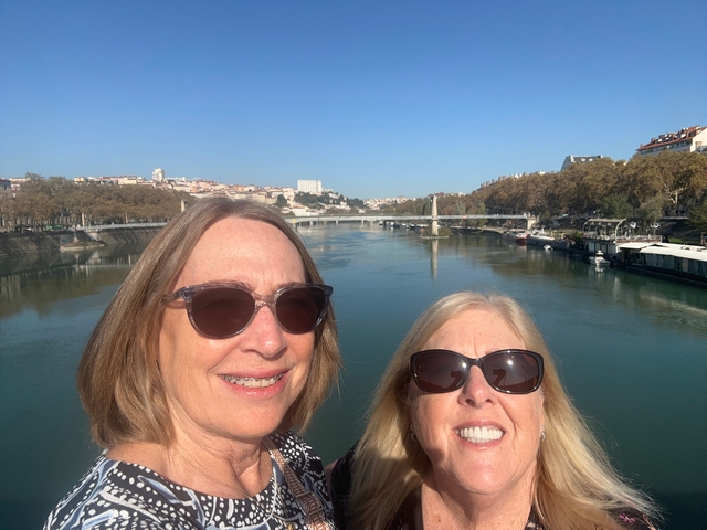 Two women smiling in front of a river