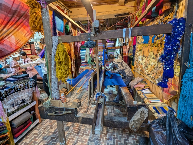 Colorful textile workshop with people working on a loom.