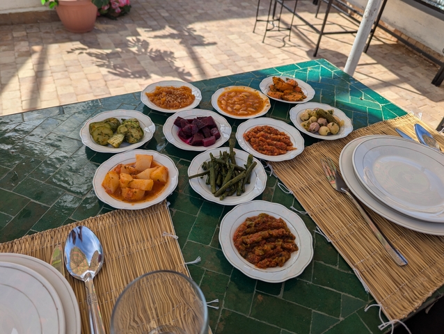 Variety of small dishes with vegetables and sauces on a green tiled table.