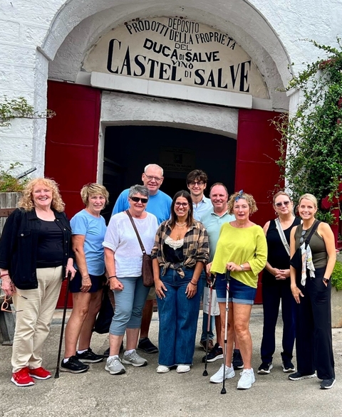       Group of people posing in front of a winery entrance.
  