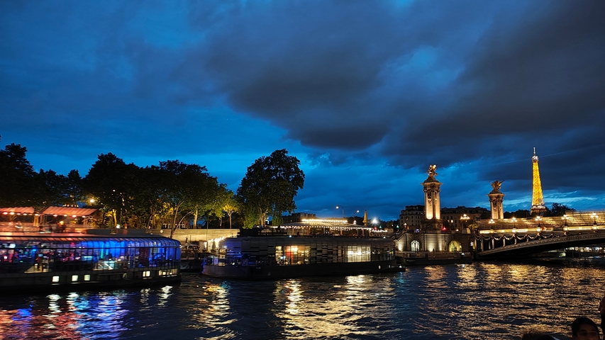       Night view of the Seine River with illuminated bridges and Eiffel Tower.
  