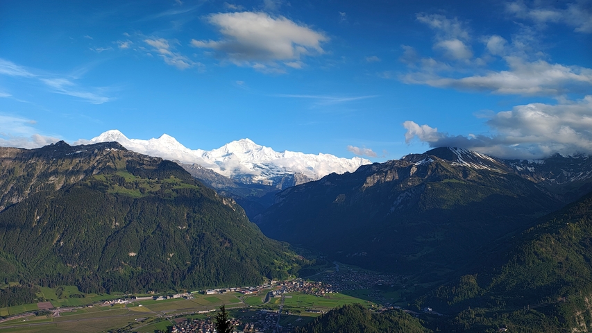 Panoramic view of snowy mountains with a village below.