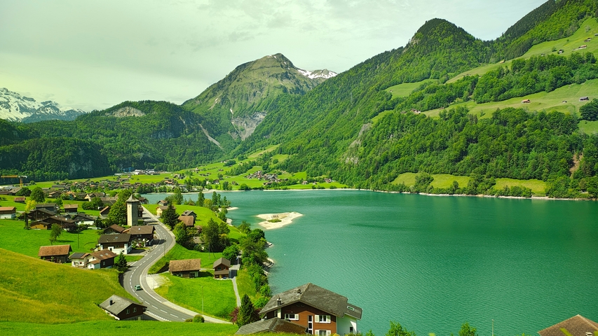       Mountain lake with surrounding hills and scattered houses.
  