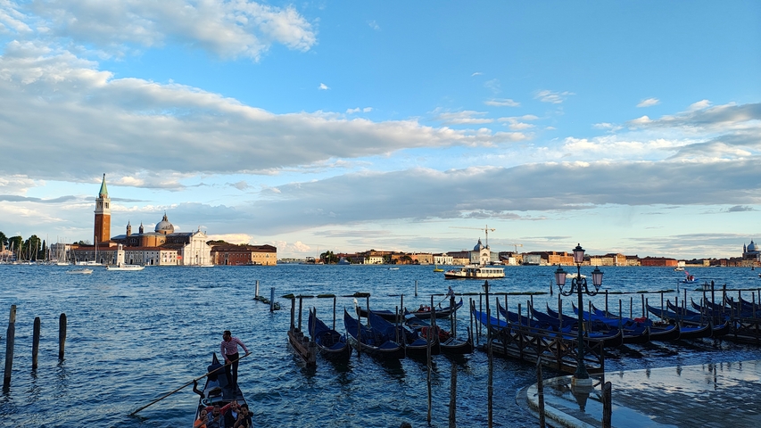 View of gondolas with a backdrop of Venice skyline and water.