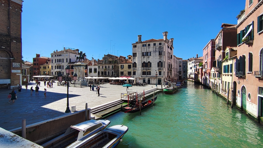       Canal view with boats and traditional Venetian buildings.
  