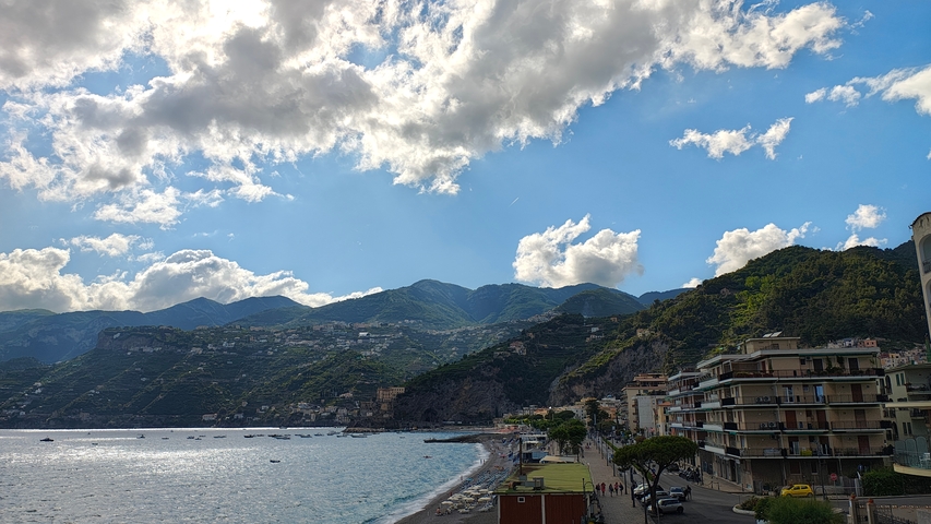 Coastline with hills and a town under a bright sky.