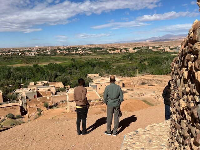 Two people looking at a village with mountains in the distance.