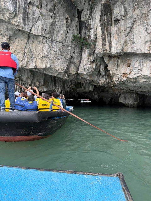 People in a boat exploring a cave by the water.
