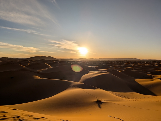       Golden sand dunes at sunset with clear sky.
  