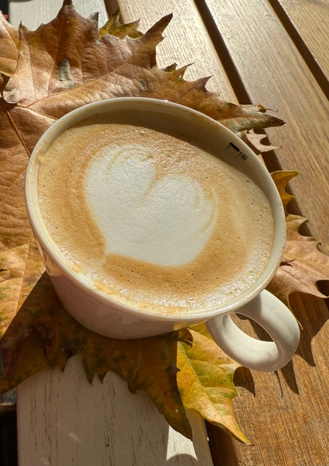 Cup of coffee with latte art and autumn leaves.