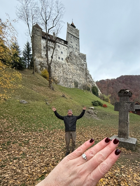       Man posing happily in front of a historic building on a hill.
  