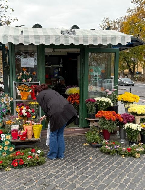       Woman selecting flowers at an outdoor stand.
  