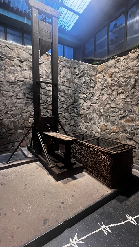 Guillotine exhibit in a stone-walled museum.