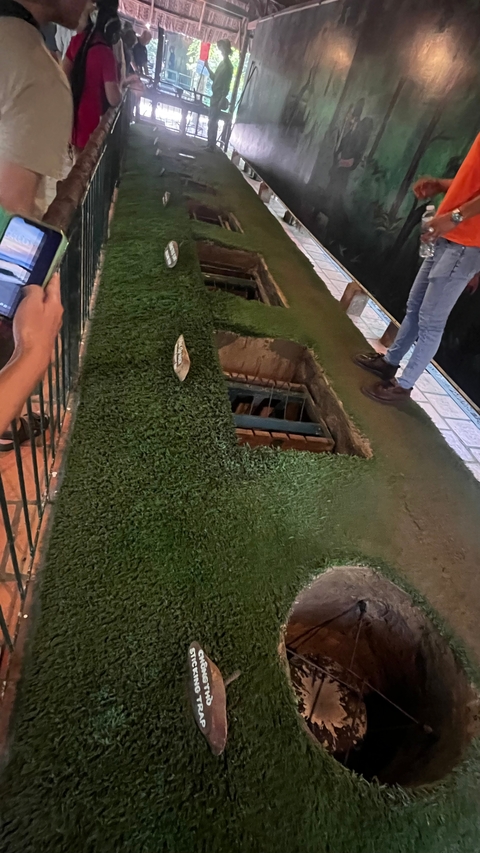       Grass-covered trapdoor exhibit with people observing.
  