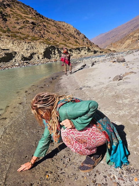 Person climbing down to a riverbed with rocky terrain.