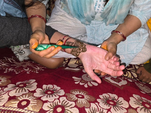 Close-up of henna being applied to a person's hand.