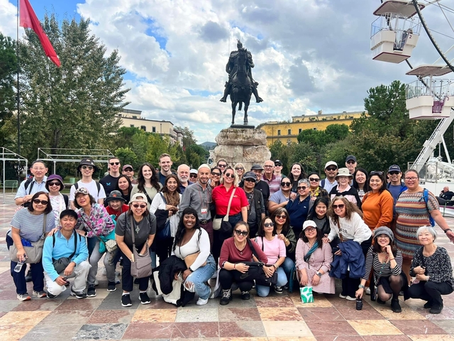       Large group posing in front of a statue in a park
  