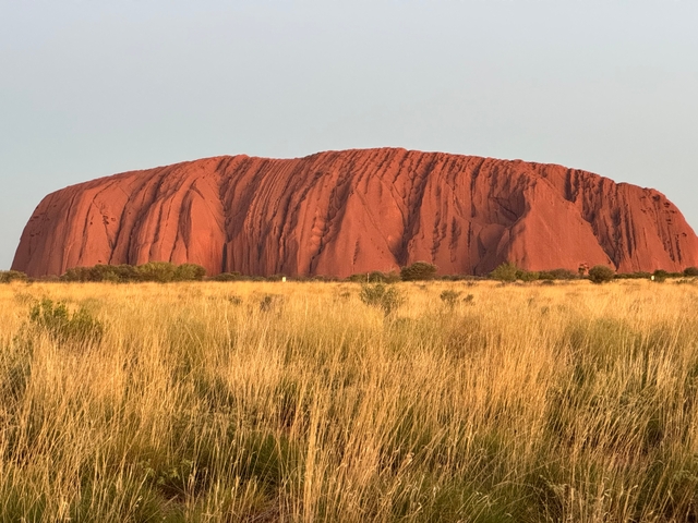 Uluru, a large sandstone rock formation illuminated by sunlight