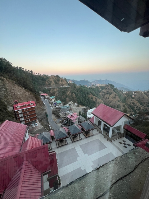 Hilly terrain with clusters of buildings under a pastel sky