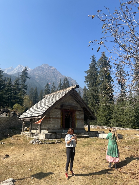 Rustic stone house with pine trees and mountain backdrop