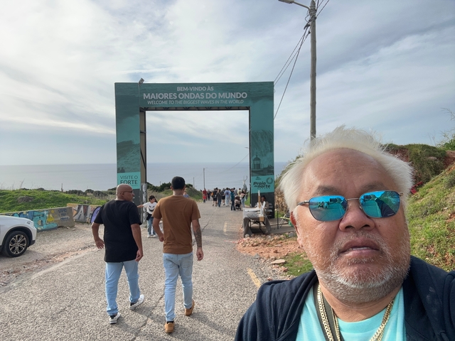 Person in front of a welcome sign at a coastal location.