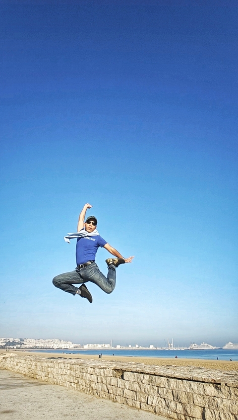 Person striking a mid-air pose against a clear sky.
