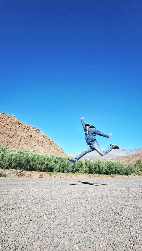 Person jumping with mountains in the background.