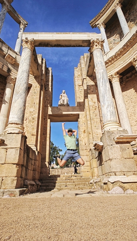 Person posing in front of an ancient structure.