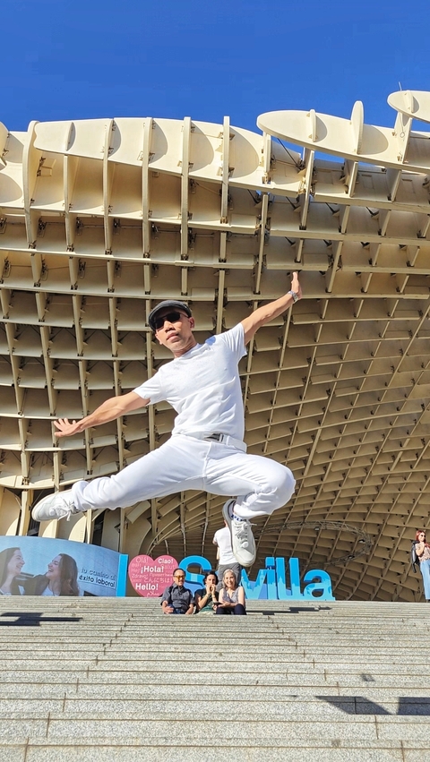 Person posing with a unique architectural background.