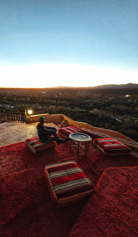 Person sitting on a terrace with a scenic view at sunset.