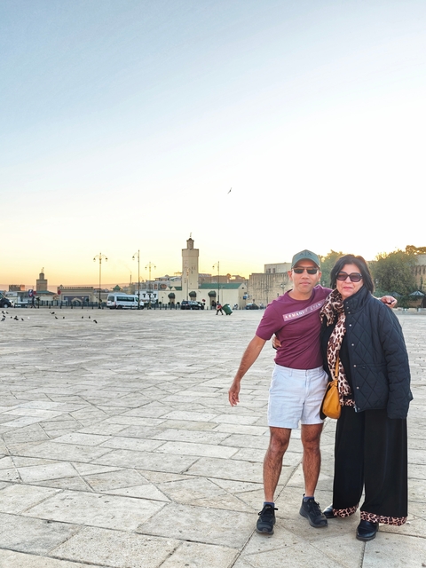 Two people standing in a plaza at sunset.