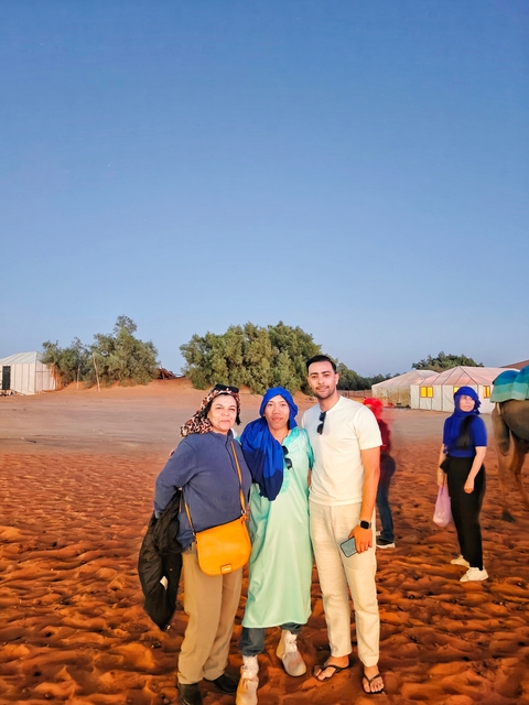       Three people posing in a desert camp.
  