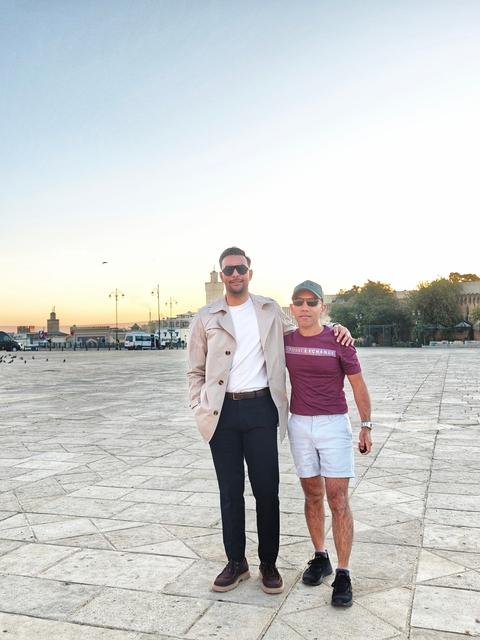 Two people standing in a plaza at sunset.