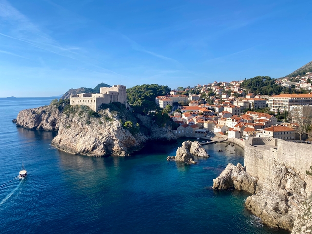 Aerial view of Dubrovnik with orange rooftops and blue sea.