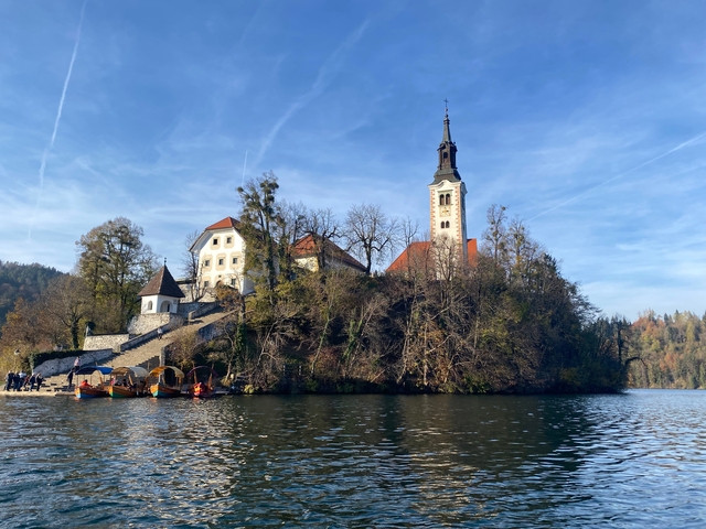 A church on an island surrounded by water and trees.