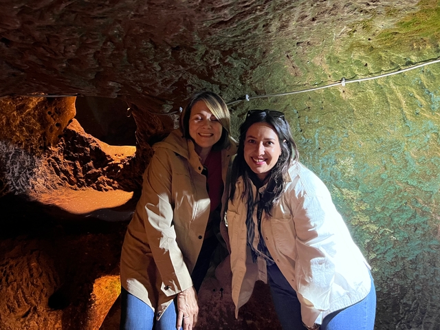       Two women in a cave with textured walls and lighting.
  
