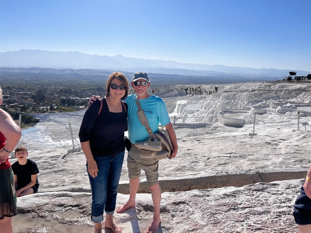       Two people posing on a white rocky landscape with mountains in the background.
  
