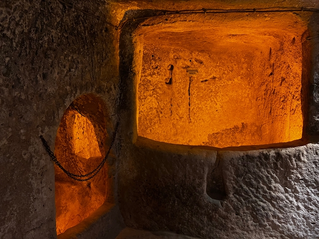       A dimly lit interior space with orange lighting and stone walls.
  