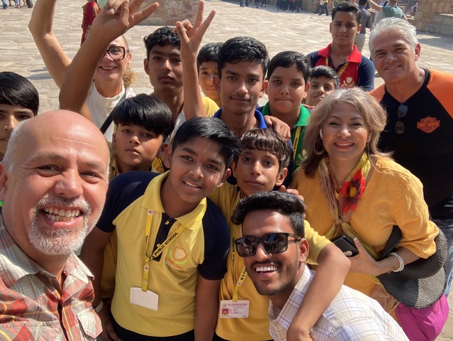 Group of people, including children, taking a selfie outdoors.