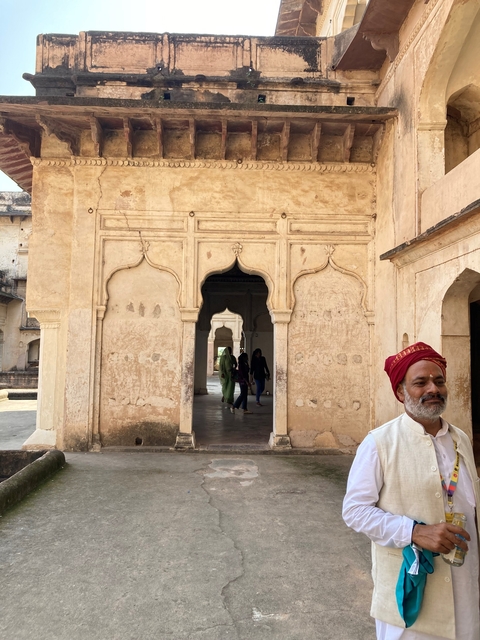       Man in traditional attire standing by a historic building.
  