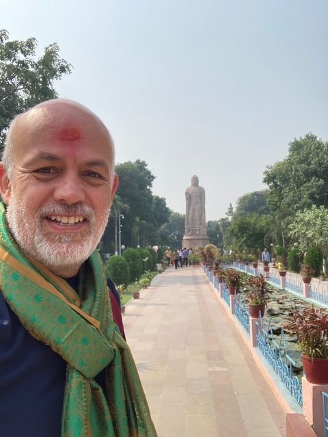       Man posing near a large statue in a garden.
  