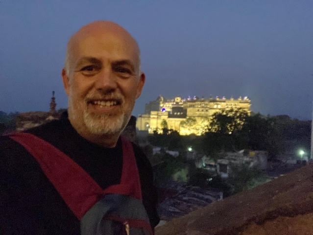       A person posing with a lit-up palace in the background.
  