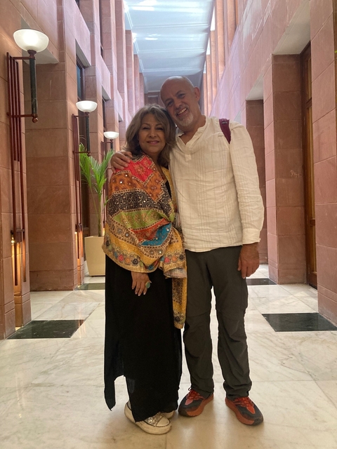       Two people posing in a modern indoor setting.
  