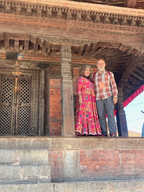       Two people standing in front of a historic building with intricate carvings.
  
