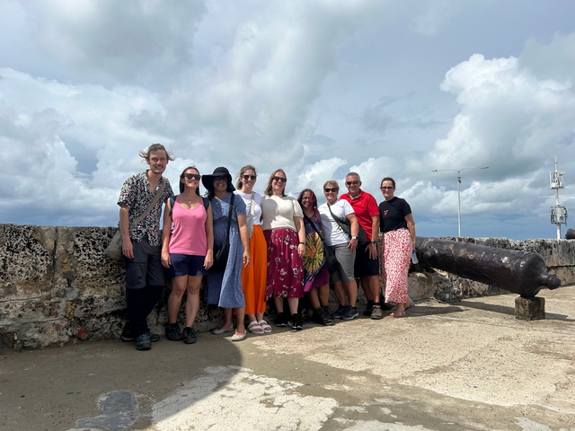 A group of people posing together outdoors with an old cannon nearby.