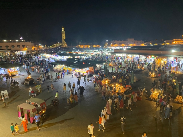       Night market with vibrant lights and crowds.
  