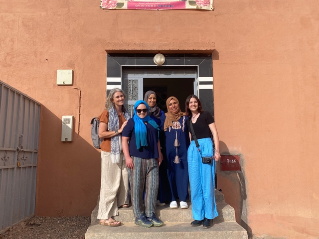       Group photo of women standing in front of a building's entrance.
  